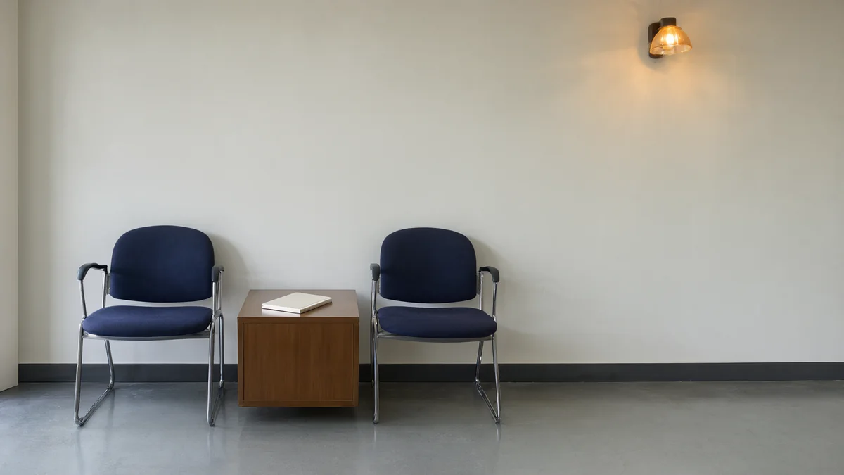 Two empty chairs beside a notebook in a quiet waiting area.