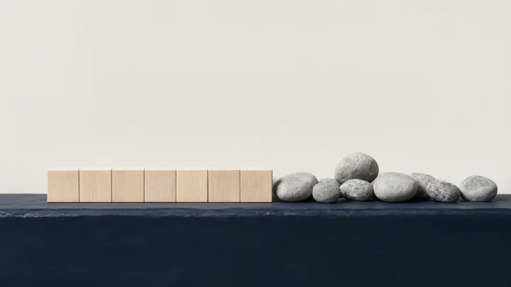 Uniform wooden blocks beside a varied group of natural pebbles.
