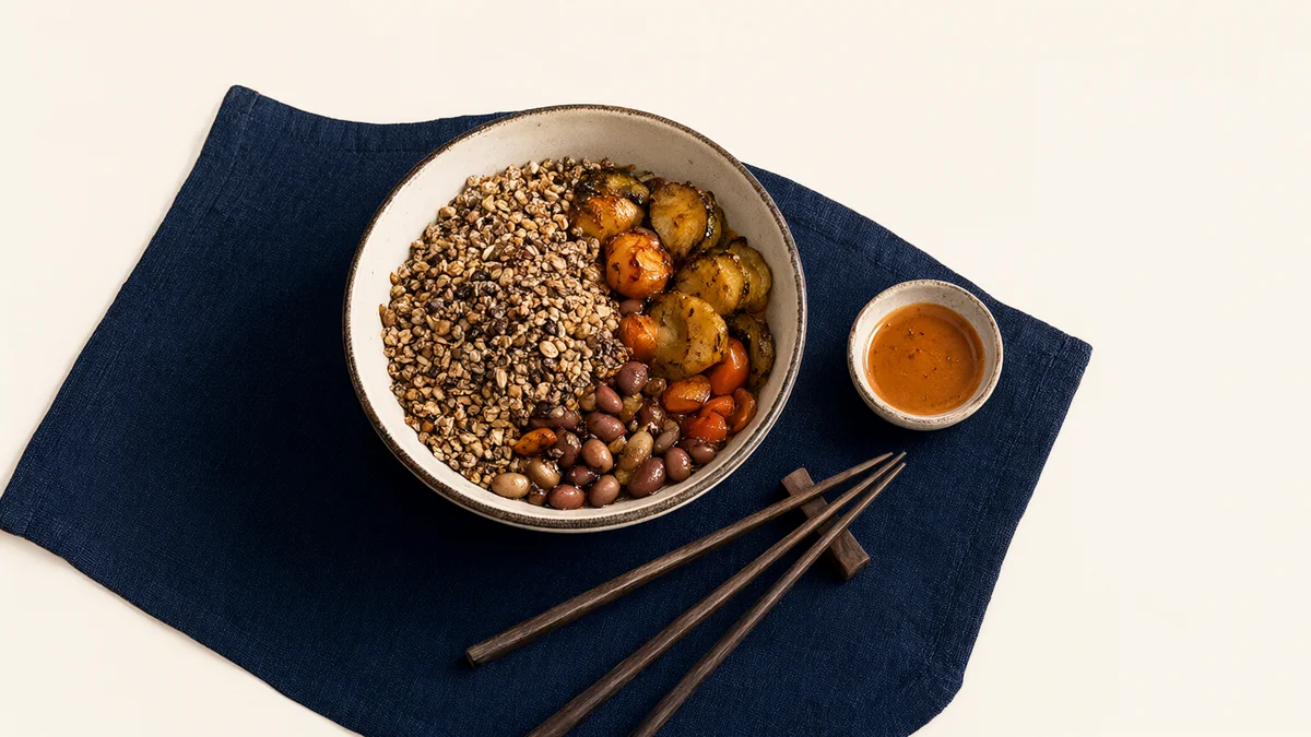 A mixed grain bowl with vegetables, beans and a sauce dish.