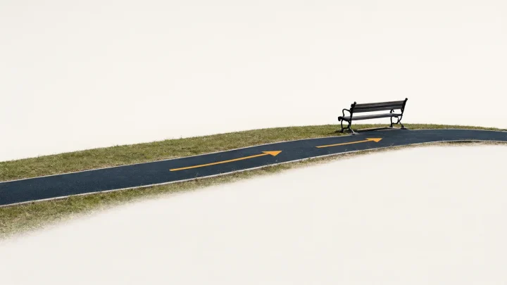 A curving park path with direction arrows and an empty bench.