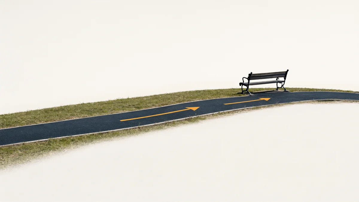 A curving park path with direction arrows and an empty bench.