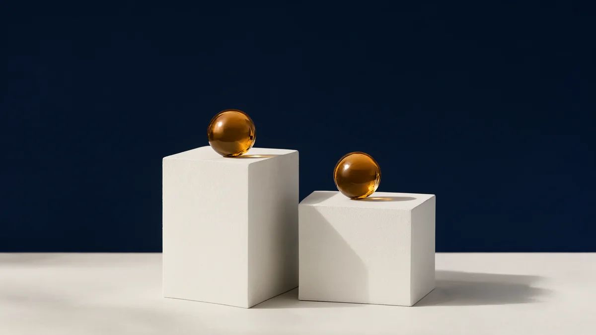 Identical amber glass spheres resting on two different pale plinths.